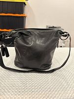 Front view of Coach black leather bag showing overall shape, strap, tassel pull