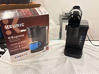 Coffee maker next to original box, power cord visible