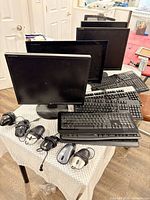 Group shot of 4 monitors, 7 keyboards, 6 mice on table
