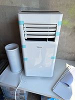 Front view of white Midea portable air conditioner showing condition and branding