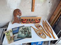 Group shot of all items: carved panel, figure board, three snowshoes, three magazines