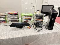 Console, Kinect, cables and three stacks of game cases