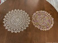 Both doilies side by side on table showing size difference and color