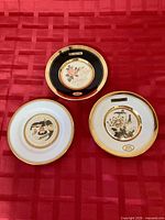 Front view of three plates showing individual motifs and gold rims