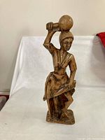 Front view of carved wooden female figure holding vessel
