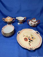 Group shot of all eight porcelain pieces on blue backdrop