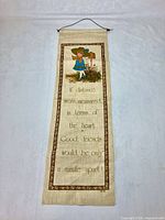Full view of linen wall hanging showing graphic, quote, border and hanging cord