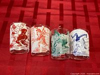 Front view of four curling cartoon shot glasses in red, orange, green, blue.