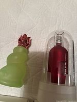 Diesel Zero Plus perfume in clear dome next to frosted green glass perfume