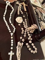 Full view of both rosaries, crucifixes, relief medallion, cherub and partial framed photo