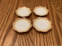 Top view of four porcelain butter pats on wooden surface