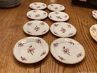 Eight small floral plates on table showing decoration and quantity