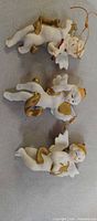 Three porcelain cherub ornaments on fabric background
