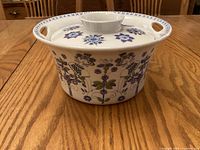 Oblique view of covered casserole showing side decoration, rim handles, lid knob