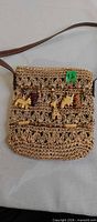 Front view showing straw weave pattern, safari animal charms, and shoulder strap