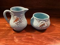 Creamer and sugar bowl front view showing relief design, turquoise interiors