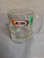 Front view of clear A&W glass mug showing logo, handle, fluted sides
