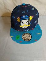 Front view showing cartoon graphic, NY logo, turquoise visor, HD sticker