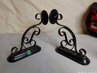 Front view of both black metal candle sconces showing scroll design and candle cups