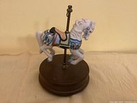 Front view of carousel horse music box, showing horse, pole, and wooden base