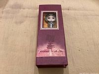 Purple presentation box with bookmark visible through window, Temple of Heaven graphic at bottom