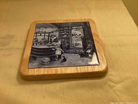 Top view of blue and white cheese-making scene tile mounted on wooden frame