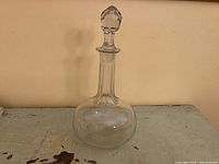 Full view of clear glass decanter with stopper in place