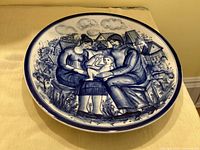 Front of blue and white ceramic wall plate showing painted family scene