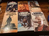 Front covers of six Louis L'Amour western paperbacks laid out on table