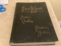 Closed hardcover catalogue showing green cloth cover and gilt titles