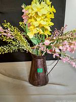 Full view of brown metal pitcher with faux floral arrangement