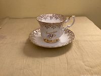 Teacup and saucer front view showing gold filigree and 50th script