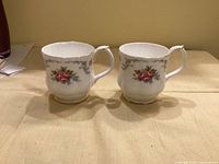 Front view of both Royal Albert Tranquility mugs showing rose motif and scalloped rims