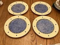 Four Royal Doulton Carmina dinner plates face up with blue felt pads on wooden table
