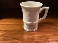 Front view of white ceramic mug showing printed blessing text and embossed Celtic knot design