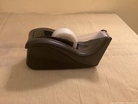 Side profile of black Scotch tape dispenser with tape roll installed