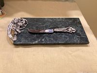 Top view of green marble board with attached pewter handle and matching knife positioned on board