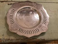 Overhead view of silver-plated tray showing crown crests and pierced rim