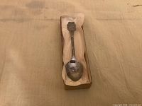 Spoon in open presentation box showing full length and crest detail