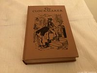 Front cover of brown cloth hardcover book with illustration and title The Clockmaker