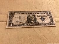 Front of $1 silver certificate showing portrait, serial number V96057914A, and blue seal