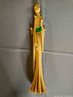 Full view of ivory-tone resin figurine showing carved details and slender form