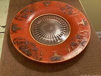 Front of plate showing orange enamel rim with decorative motifs and clear starburst center