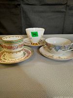 Three teacups with matching saucers, different floral patterns, gold accents