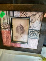Front view of framed botanical print showing leaf motif, patterned background and dark wood frame