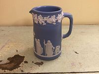 Front view of blue Wedgwood jasperware cream jug showing white relief decorations