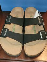 Top view showing two-strap black suede Birkenstock sandals with buckles and tag