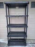 full view of black plastic shelving unit showing four shelves and uprights