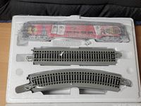 Train car and two curved track pieces sealed in styrofoam insert