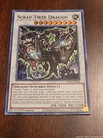 Front of Scrap Twin Dragon card showing artwork, card text, set code, ATK/DEF and 1st Edition stamp